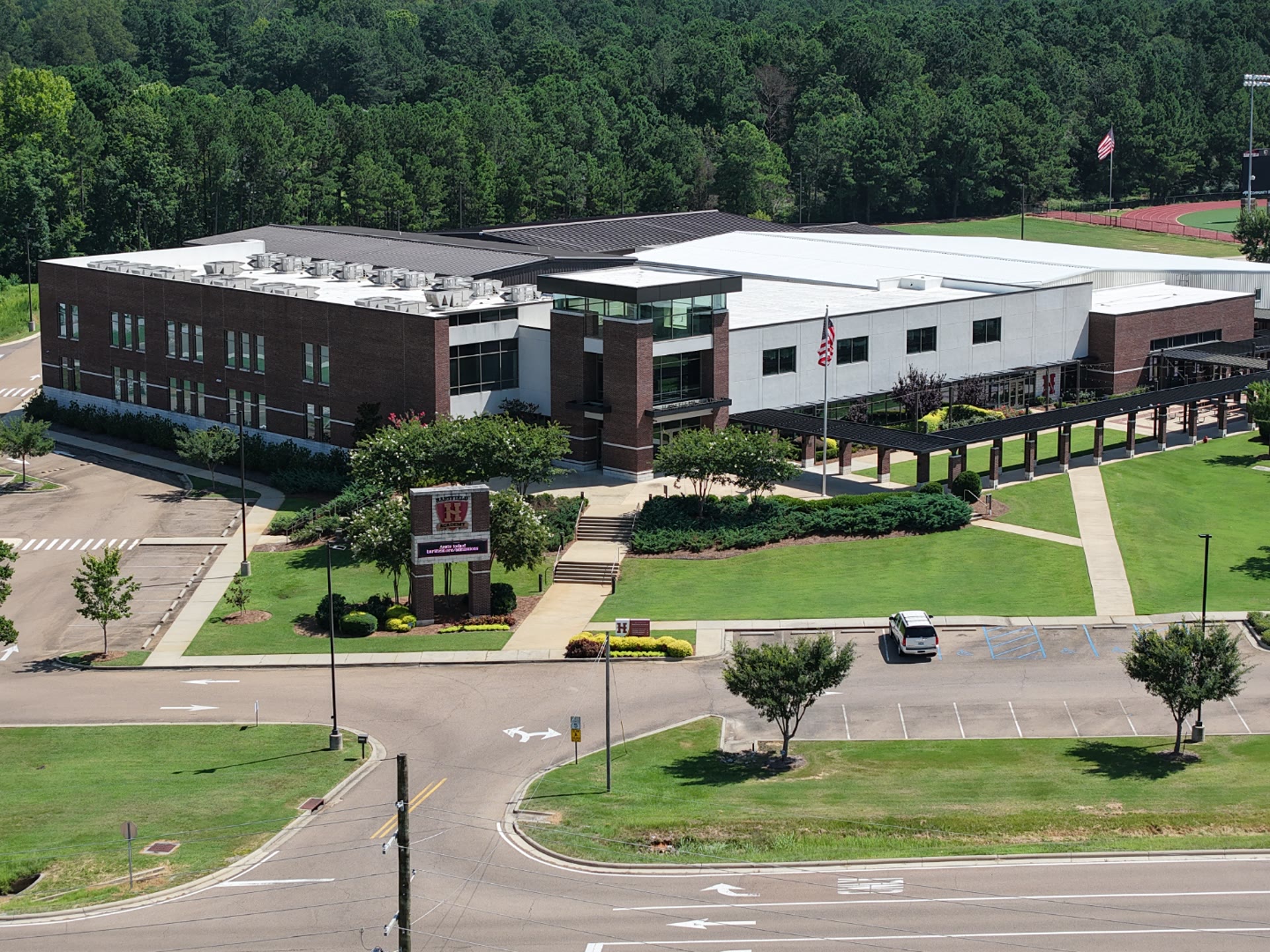 Aerial drone view of a residential property and neighborhood under a wide blue sky in Central Mississippi