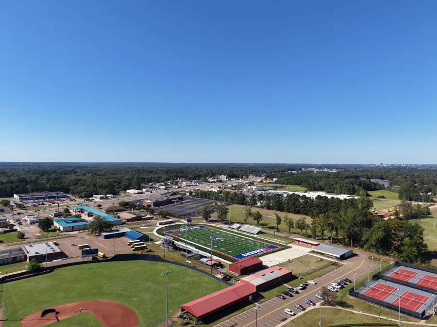 Wide panoramic aerial view of a community athletic complex and surrounding town