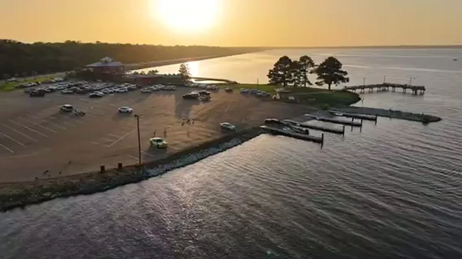 Aerial view of a waterfront marina, pier, and parking area at sunset
